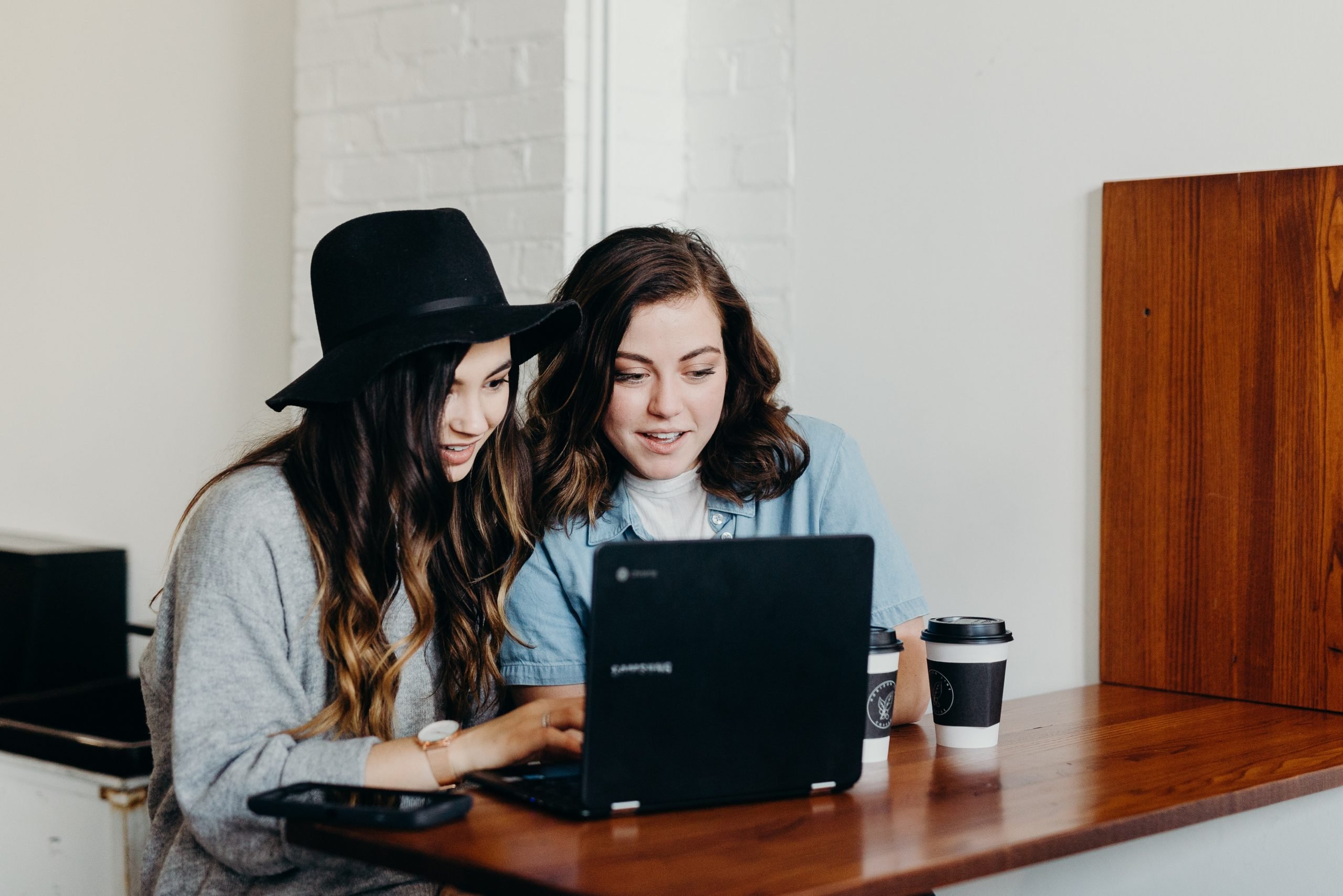 2 girls have just started a blog and sitting in front od the black laptop