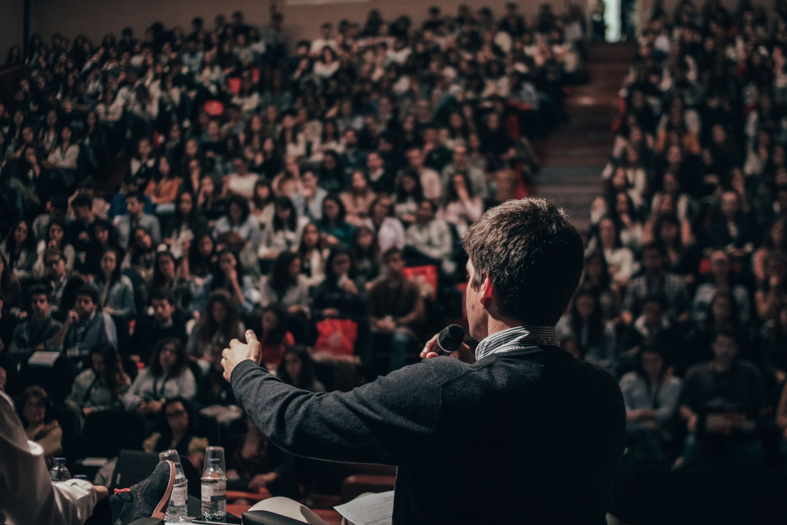 Speakers is standing on the stage and talking to his audience